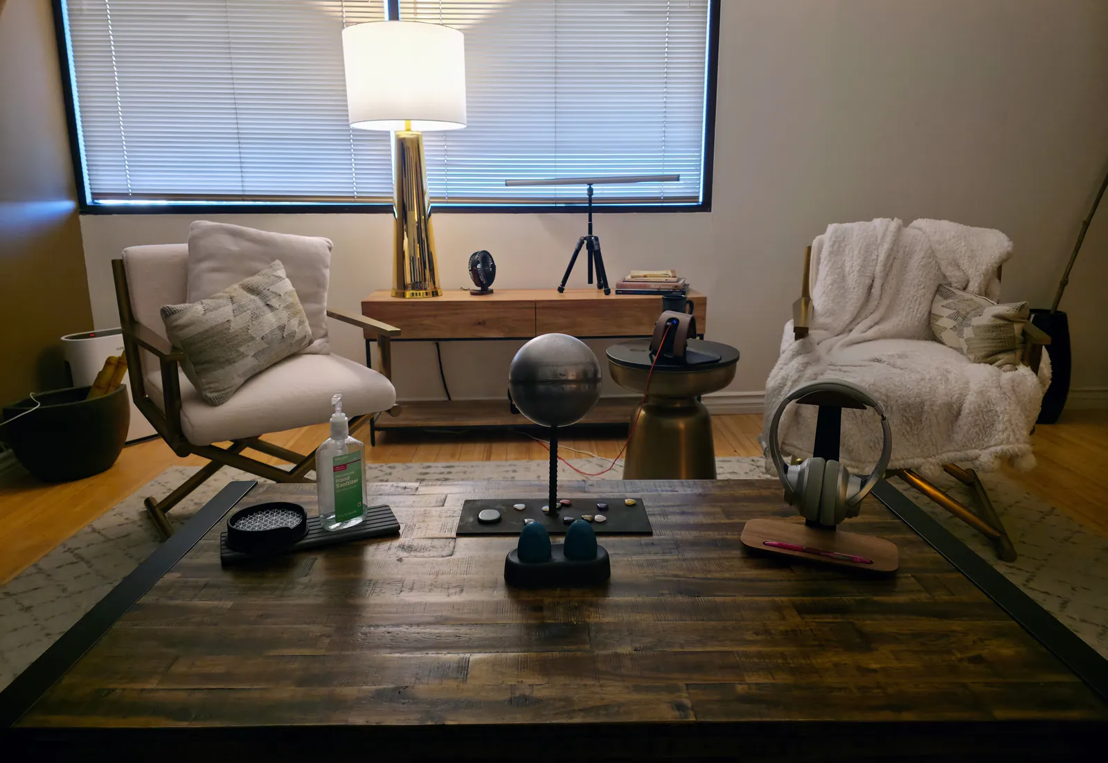 The therapy office: two armchairs facing a wooden table, with the EMDR light bar on its stand by the window and the tappers and headphones on the table.